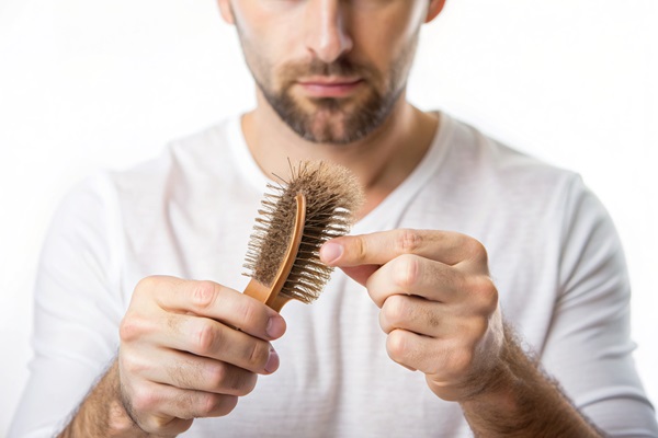 Caída del cabello por Covid - Hombre quitando las hebras de cabello que se quedan en el cepillo, debido a una caída de pelo anormal