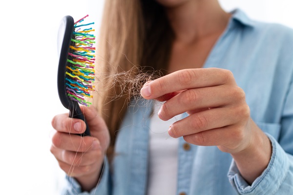 Reparar el cabello dañado - Mujer observando que pierde cabello al peinarse, debido al daño capilar que presenta