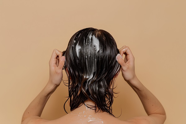 Mujer aplicando una mascarilla capilar de aceite de soja y ricino, para nutrir y fortalecer el pelo
