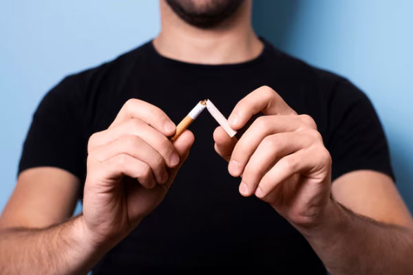 Foto de un hombre de camiseta negra rompiendo un cigarrillo con las manos