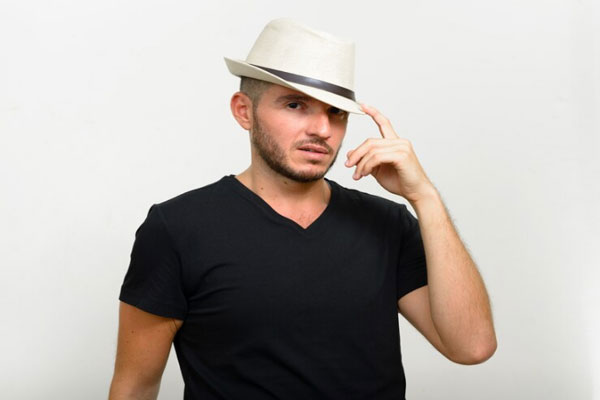 Hombre hispano con camisa negra usa un sombrero de lado para protegerse del sol