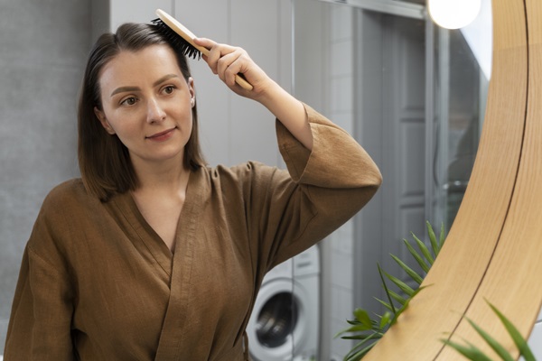 Mujer peinando su cabello de manera suave, para evitar causar daño a los folículos pilosos