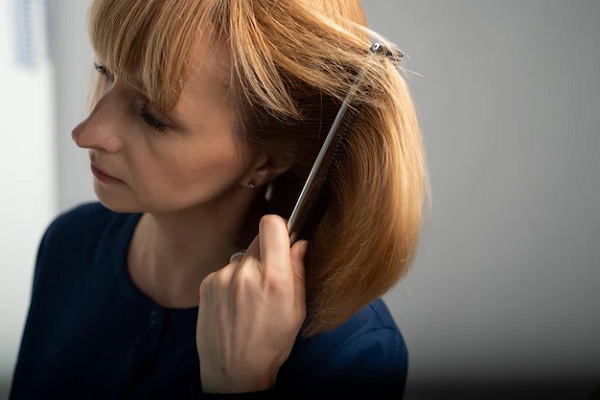 Alopecia en la menopausia - Mujer de rostro perfilado utiliza un peine para cuidar y desenredar su cabello