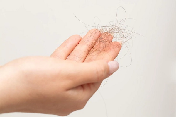 Alopecia en la menopausia - Plano detalle una mano de mujer sosteniendo una pequeña bola de pelos