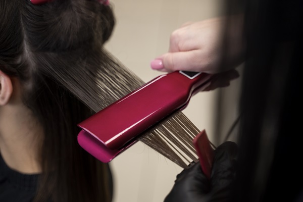 Caída del cabello - Estilista usa una plancha de cabello para alisar el pelo de una mujer
