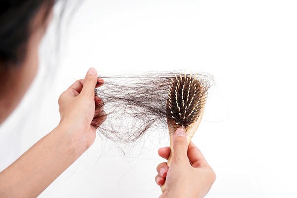 Caída del cabello - Persona quitando el cabello que se queda en el cepillo luego de peinar el pelo
