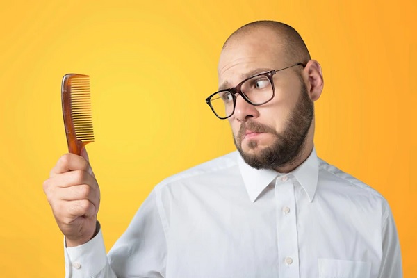 Efecto shedding - Hombre calvo de lentes mira un peine con tristeza