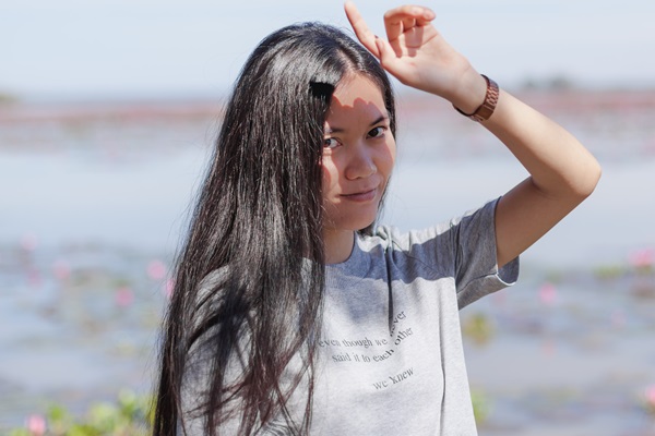 Caída del cabello - Mujer con cabello negro y sedoso levanta su mano para protegerse del sol