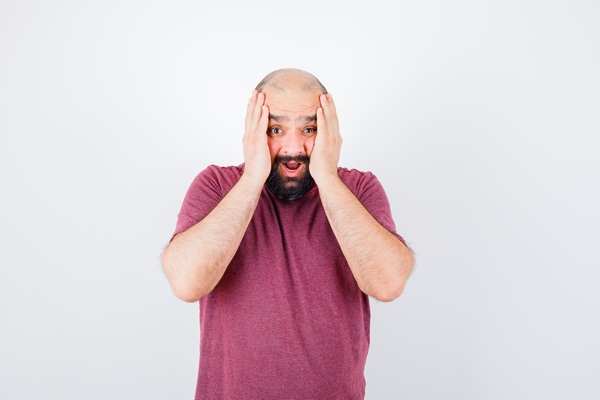 Hombre con alopecia coloca sus manos en la cara con gestos de asombro