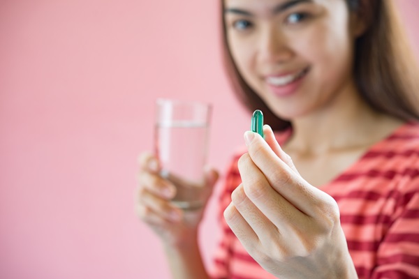 Espironolactona - Mujer sosteniendo una pastilla y un vaso de agua para ingerirla, como parte del tratamiento médico