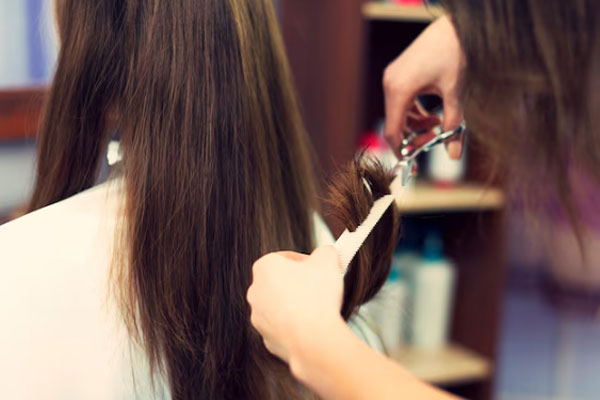 Estilista profesional trabaja en un corte de puntas para mejorar el aspecto del cabello de una cliente
