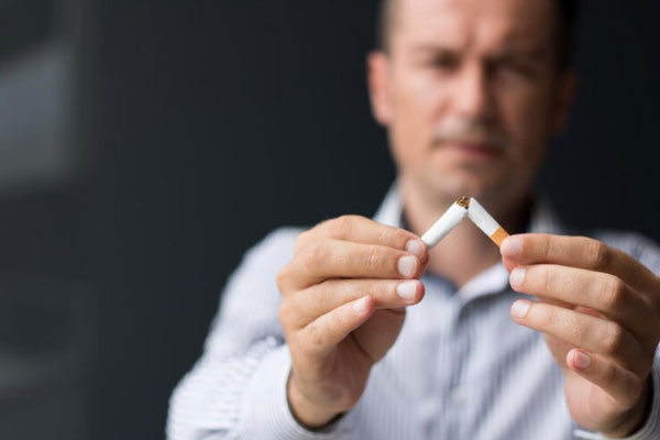 Hombre rompe un cigarrillo a la mitad para dejar de fumar