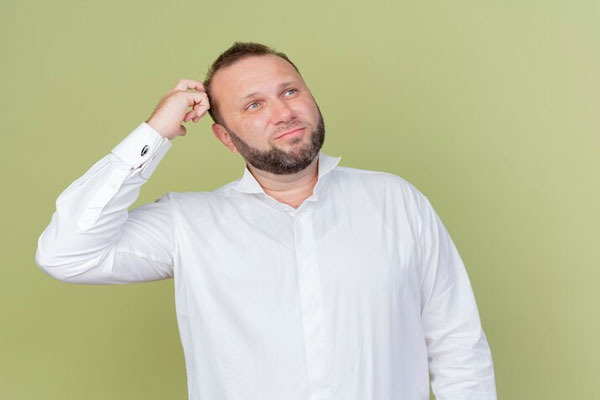 Alopecia y circulación sanguínea - Hombre de camisa blanca con principios de calvicie se muestra pensativo 