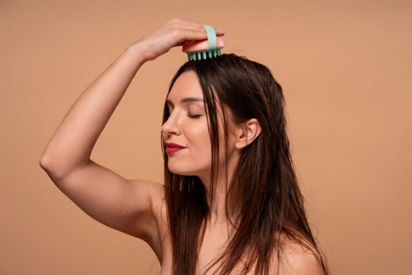 Alopecia en la menopausia - Mujer de labios rojos utiliza un masajeador para mejorar la irrigación sanguínea que llega a su cabeza