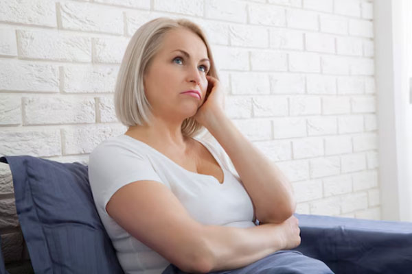 Alopecia en la menopausia - Mujer adulta y de cabello corto se muestra pensativa mientras descansa en el sofá