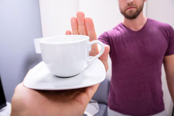 Joven rechaza una taza de café con la mano