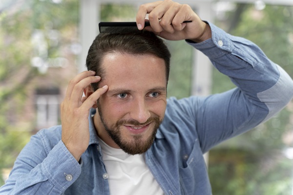 Hombre joven usa un cepillo para peinar su cabello negro