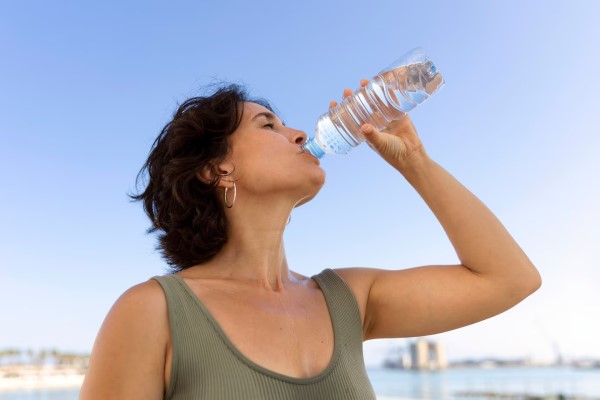 alimentos que causan la caída del cabello - mujer adulta bebiendo agua en un día de calor
