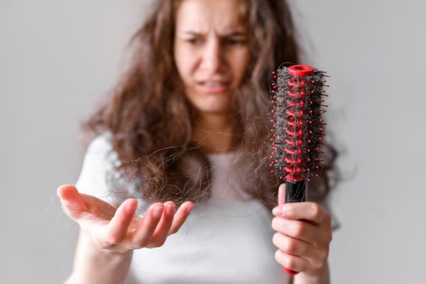 contaminación - joven mirando preocupada el mechon de cabello en su mano y los restos en el cepillo de su mano