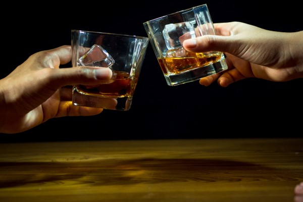 alimentos que causan la caída del cabello - hombres brindando con unos vasos con whisky y hielo