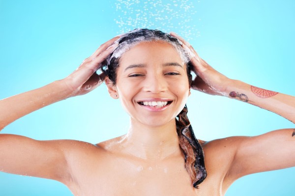 Alopecia Seborreica - mujer sonriente enjabonándose la cabeza