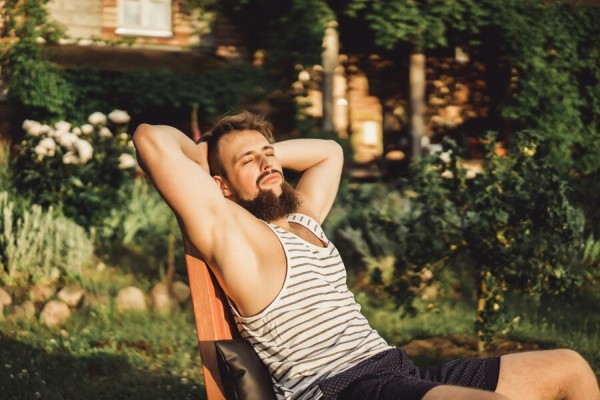 hombre sentado en una hamaca en el jardín descansando al sol