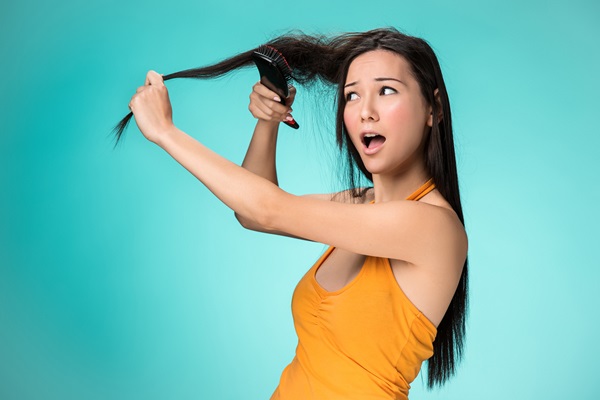 Hair slugging - Mujer joven frustrada usa un cepillo para desenredar el pelo
