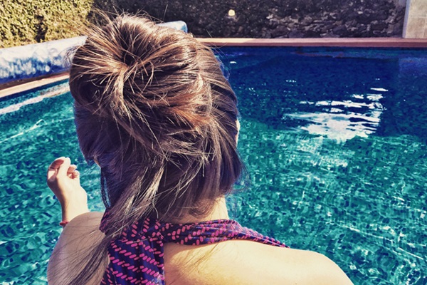 Mujer de cabello rubio con un peinado de moño junto a la piscina