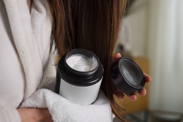 Hair slugging - Mujer de pelo cobrizo sostiene en sus manos un recipiente de crema hidratante