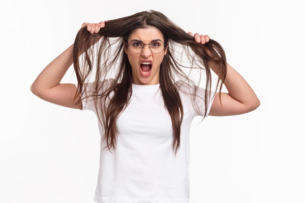 Hair slugging - Mujer joven con lentes jalando su cabello con cara de desesperación