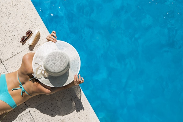 Cloro de las piscinas - Mujer con sombrero acostada en el borde de la piscina