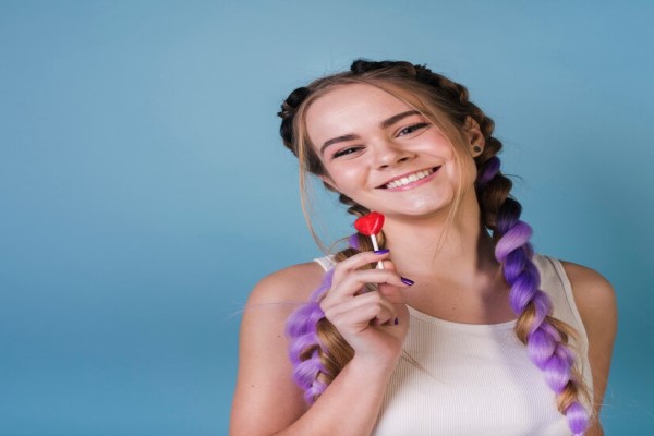 Peinados que debes evitar - mujer joven sonriente con dos largas coletas multicolores