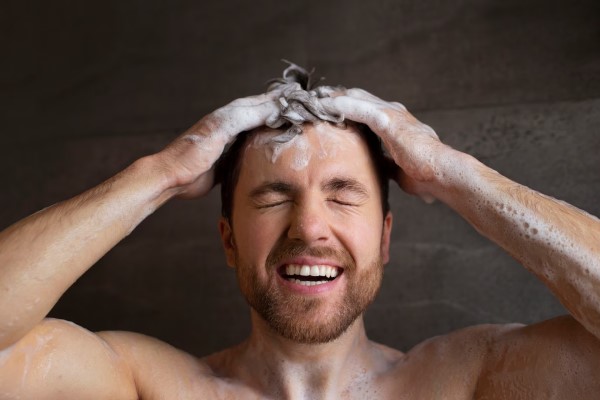genes causantes de la alopecia - hombre enjabonándose el cabello en la ducha