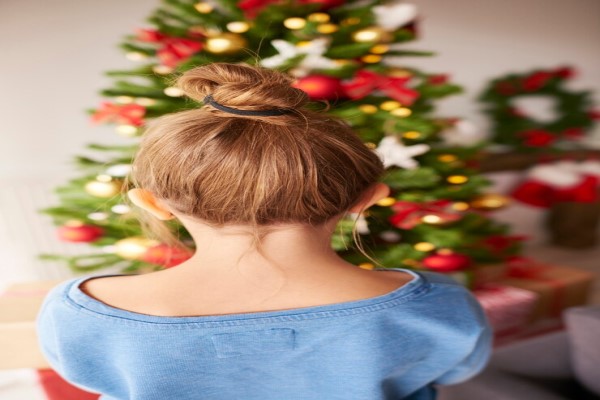 Peinados que debes evitar - niña peinada con un moño mirando el árbol de navidad