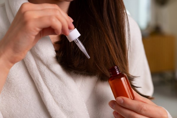 mujer aplicando un tratamiento capilar con cuentagotas en su cabello