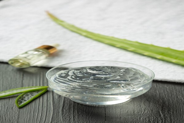 Beneficios del aloe vera en el pelo - bol con una crema de sábila al lado de una toalla con un tónico capilar