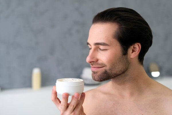 Hombre con buen volumen capilar sostiene una mascarilla para garantizar la hidratación del cabello