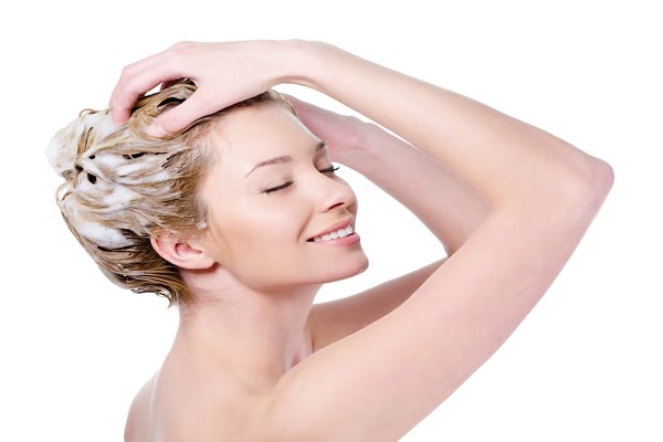 mujer sonriente enjabonándose la cabeza