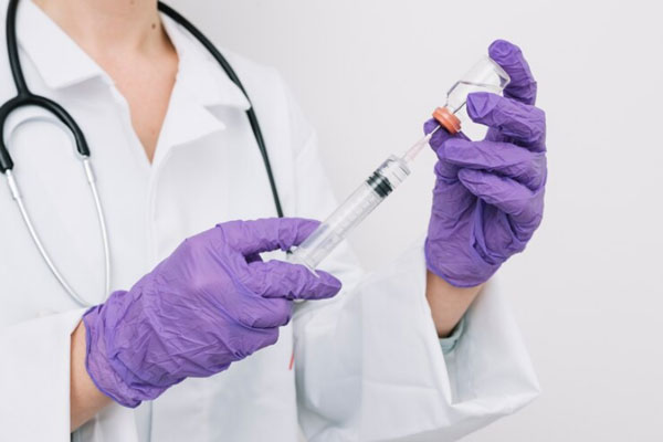 Esteroides anabólicos - Doctora usa una jeringa para administrar una dosis de hormona del crecimiento en versión inyectable