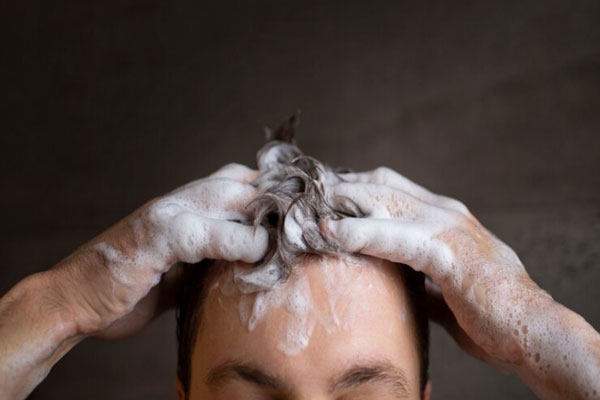 Plano detalle de la cabeza de un hombre lavando su cabello con champú