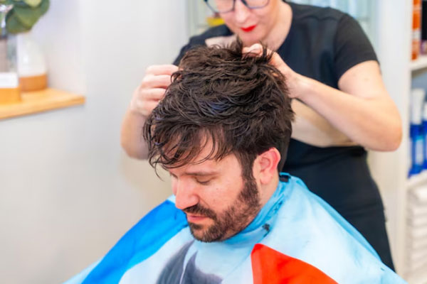 Sistema de integración capilar - Estilista corta y da forma al cabello postizo de un hombre con problemas de alopecia