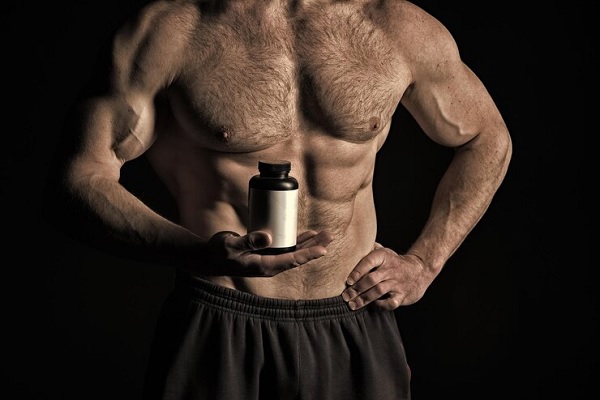 Esteroides anabólicos - Hombre toma testosterona en versión sintética para mejorar la proyección de triceps y biceps