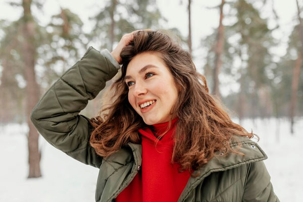 Joven se peina la cabellera mientras sale a dar un paseo en temporada de nieve 