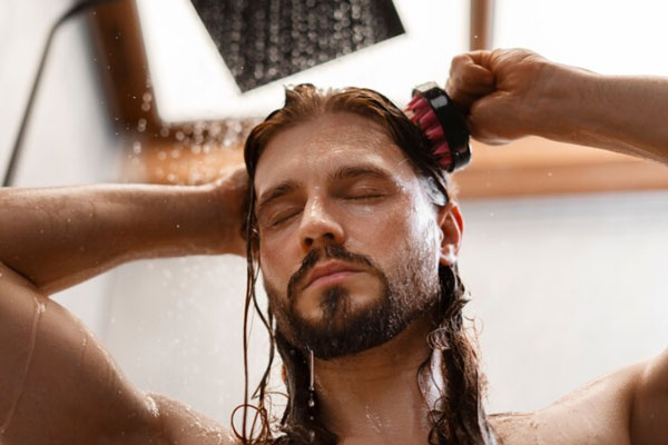 Hombre de cabello largo lava y masajea su cuero cabelludo para preservar su salud capilar
