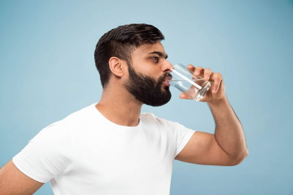 Hombre toma vaso de agua para mejorar la oxigenación del cuero cabelludo