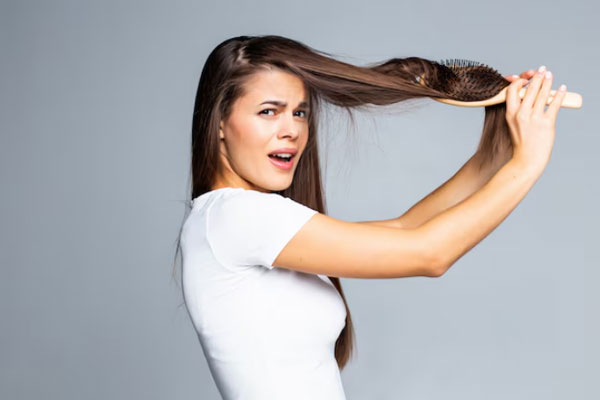 Desenredar el pelo - Joven con cepillo en mano intenta deshacer un gran nudo de cabello 