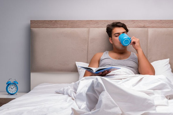 Hombre lee un libro para conciliar mejor el sueño antes de irse a dormir