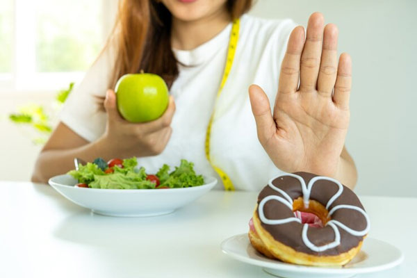 Mujer rechaza un plato de donas mientras trabaja en un cambio de hábitos alimenticios