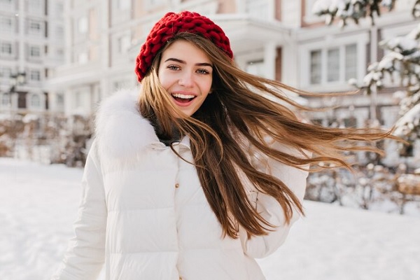 Cabello en invierno - Joven con gorro y pelo liso sale a dar un paseo en la estación más fría