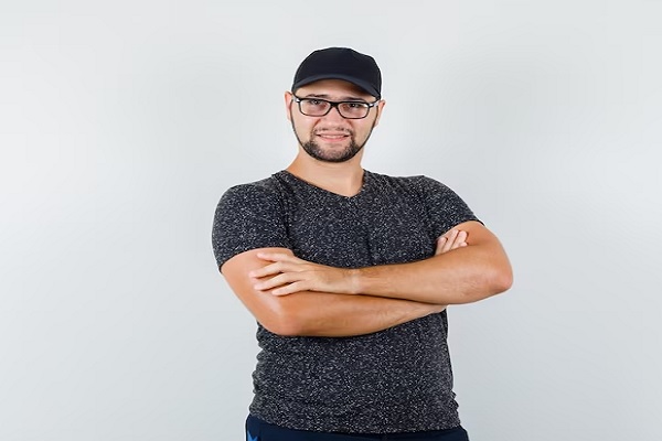 gorra tras el injerto capilar - hombre con los brazos cruzados y una gorra muy ajustada algo perjudicial para los folículos capilares tras el injerto capilar